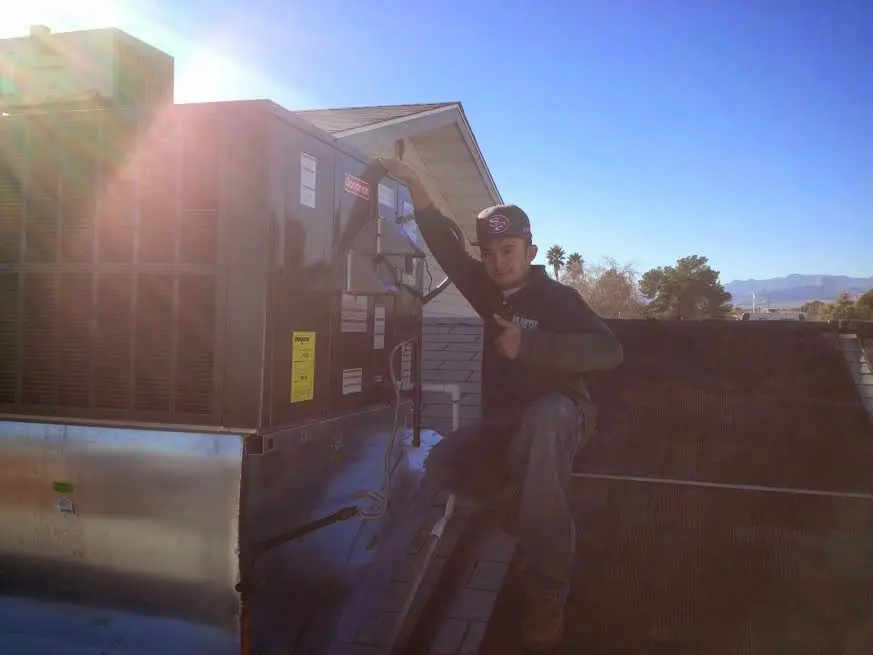 HVAC technician performing AC Tune-Up on a rooftop unit in Fredericksburg
